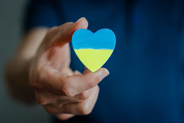 Ein Mann hält ein blau und gelb bemaltes Herz. Ukraine.