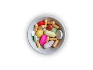 A white bowl of various colorful pills and capsules isolated on white background.