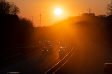 Sunset above german Autobahn A46 in Sauerland. Curved 4-lane motorway with passing cars in orange...