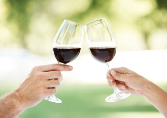 To us. Cropped view of a couples hands toasting with two glasses of wine.