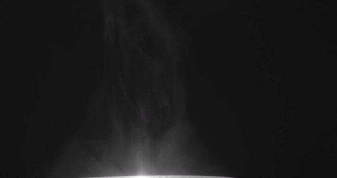 smoke and dust rising up from cooking pot in front of black background in 4k. Shot at 60fps. Hot steam.