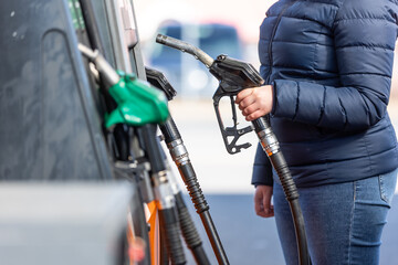 High prices of petrol and diesel fuel ath the petrol station, young woman refueling the car,...