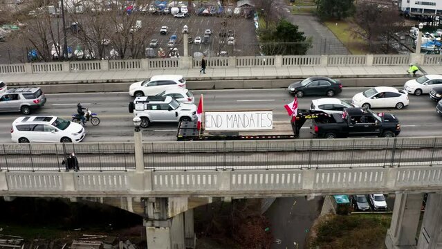 Pickup Vehicle Towing Flatbed Truck With Canadian Flags And End Mandates Banner. Truckers Convoy Protest At Burrard Bridge In Vancouver, Canada. aerial drone