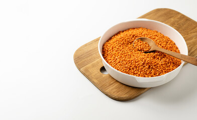 dry orange lentils in a white bowl on a white background, space for text