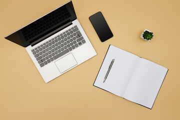 Office desk working space. Top view of office desk table with laptop, smartphone, open notebook and plant on the side. Blank notebook page for input the text in the middle. Copy space