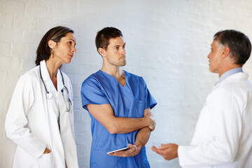 Theyre in the business of saving lives. A cropped shot of three doctors standing and having a serious conversation.