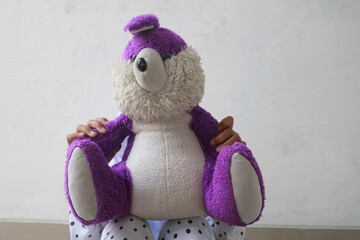 Close-up of purple buny doll with child girl. She is covering her face with a purple doll. A very scared little girl. Depression, violence, domestic violence, child abuse concept. 