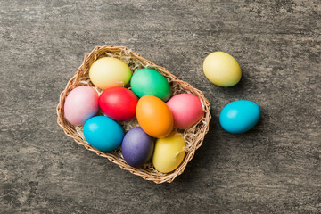 Multi colors Easter eggs in the woven basket on colored background . Pastel color Easter eggs. holiday concept with copy space