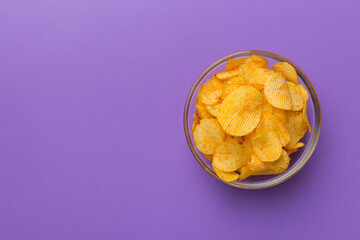 Potato chips on bowl isolated on colored background. Delicious crispy potato chips in bowl. Space for text. Top view