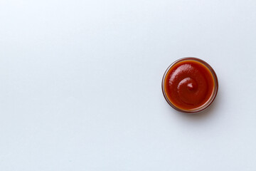 Bowl of ketchup or tomato sauce on colored background, top view with copy space
