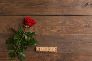 Naklejka na ściany i meble Red rose with Inscription March on wooden cubes on the wooden background. International Women's Day, March 8. Copy space.