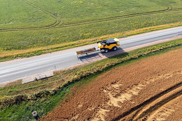 combine harvester on the road between agricultural fields, aerial view