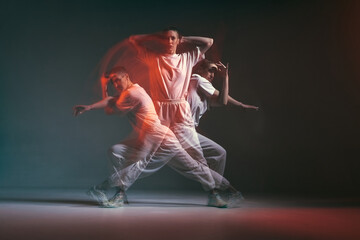 Naklejka na ściany i meble Dancing young sporty girl moving in fiery hip-hop dance in red neon studio light. Long exposure. Breakdancing school ad