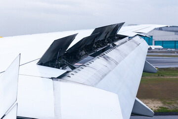 The wing of an aircraft with open flaps on the wing that is landing.