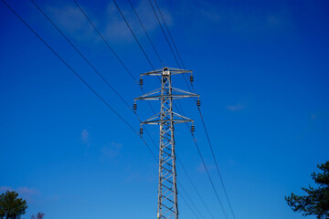 Looking up at  a electricity pylon with blue sky background 