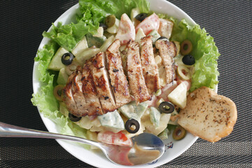 Grilled chicken and fresh vegetable salad on table.
