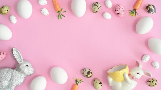 Spring Easter holidays background with eggs and rabbits copy space frame on pastel pink theme. Stop motion flat lay
