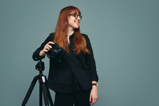 Professional photographer standing next to her tripod in a studio