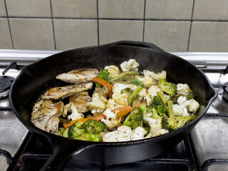 Mixed vegetables and chicken being cooked on a skillet
