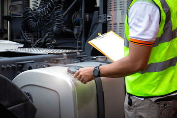 Auto Mechanic is Checking the Semi Truck's Fuel Tank Trucks. Daily Maintenance Checklist. Fixing.....