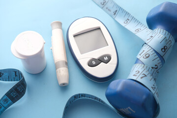 Close up of diabetic measurement tools and dumbbell blue background 