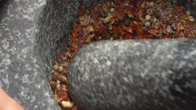 Super close-up of a pestle grinding and mixing various kinds of spices