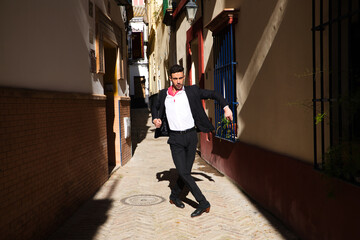 Obraz premium flamenco and gipsy man, dressed in black and white shirt and red polka dots handkerchief dancing flamenco in an alley in the streets of a mediterranean city. Flamenco cultural heritage of humanity.