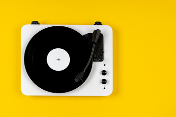 Vinyl turntable with vinyl plate on a yellow background. Modern gramophone record player. Retro...
