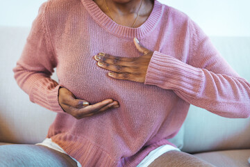 Young African American woman palpating her breast by herself that she concern about breast cancer....