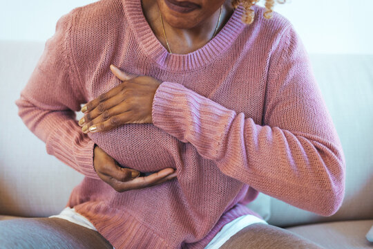 Young African American woman palpating her breast by herself that she concern about breast cancer. Healthcare and breast cancer concept. Mature woman doing self breast exam at home