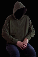 Fototapeta na wymiar Faceless person in hoodie sitting in the darkness with hands crossed. Mystery man with hood. Hooligan in hoodie. Crime and violence concept