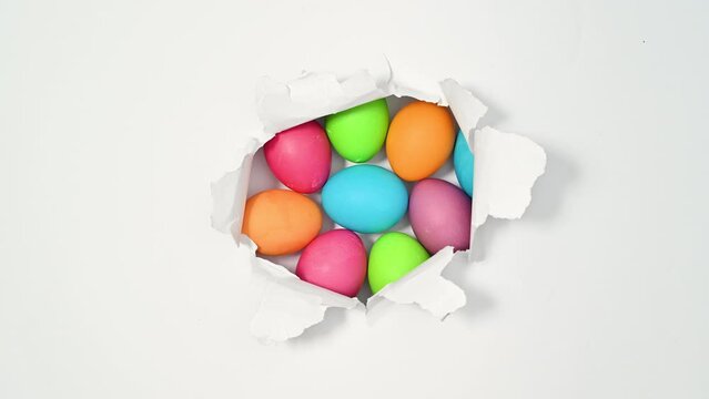 Tearing up white background with colorful Easter eggs inside. Creative holidays stop motion