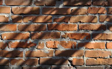 An old wall sloppily built of red brick covered with shadow