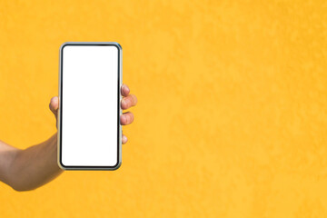 Close-up, Mockup of a smartphone in a girl's hand. Against the background of a yellow facade made of decorative plaster.