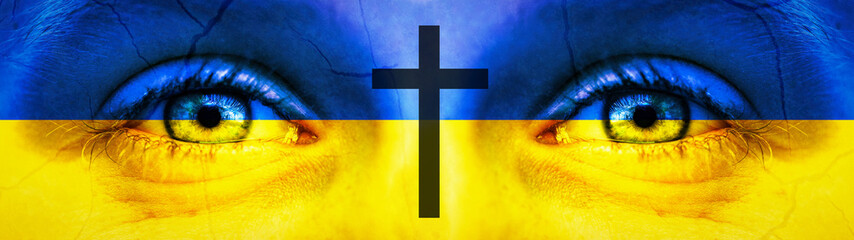 War in Ukraine background banner panorama - Close-up of child's eyes in the colors of Ukrainian flag, with tears, cracks cross