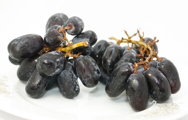 Close up, ripe bunch of black grapes with shining drop of water isolated on white background