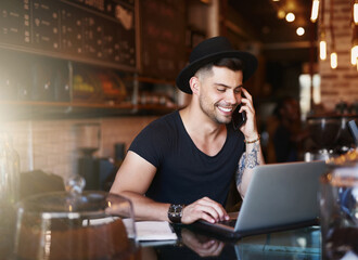 In the coffee industry, the best go wireless. Shot of a young man using a phone and laptop while working in a coffee shop.
