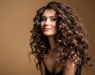 Curly Hair Model. Woman Wavy Long Hairstyle. Brunette Fashion Girl with Volume Hairdo and Natural Make up over Beige Background - obrazy, fototapety, plakaty