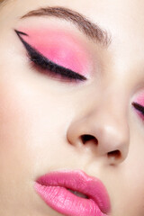 Closeup macro shot of human female face with pink makeup. Eyes closed.