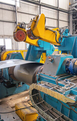 Cutting machine with roll of galvanized steel sheet. Ironworks and metalwork manufacturing factory for production of metal pipes and tubes, industrial concept