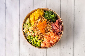 Mixed Norwegian Salmon and Bluefin Tuna Poke Bowl with Crispy Onion, Tobiko Masago Roe, Ripe Mango, Diced Mexican Avocado, White Rice, Wakame Seaweed and Edamame Beans in a Delivery Container