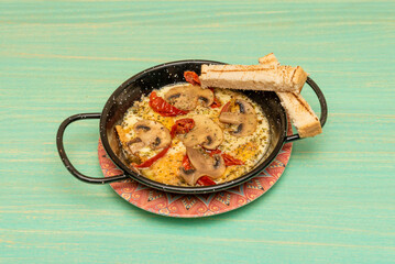 Great Italian recipe for a portion of roasted provolone cheese in a container along with mushroom slices, after tomato, a lot of oregano and toasted bread for dipping