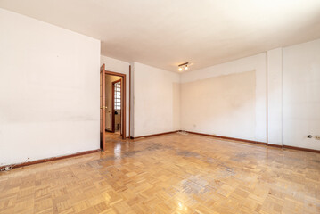 Large empty room in need of a good coat of paint on the walls and a slash on the parquet floor