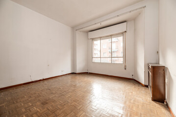 empty room with a mahogany wood radiator cover, a large window of old windows and empty rails on the ceiling