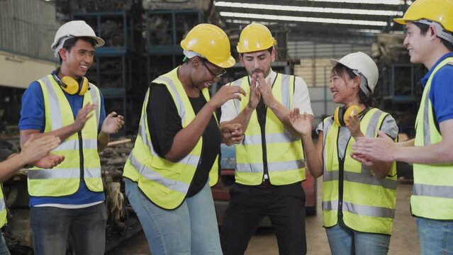 happy young factory worker with colleagues. Group of happy workers in uniform at factory. Dance.