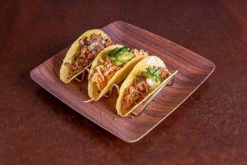 assorted mexican tacos with crispy tortillas, cilantro, shredded beef, guacamole and red onion