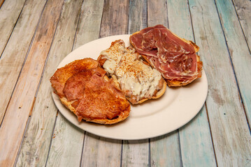 Assorted Spanish toasts with Serrano ham with olive oil, another with lacon with pepper and another with loin with melted goat cheese