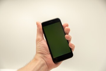 Hand holding blank smartphone display against white background