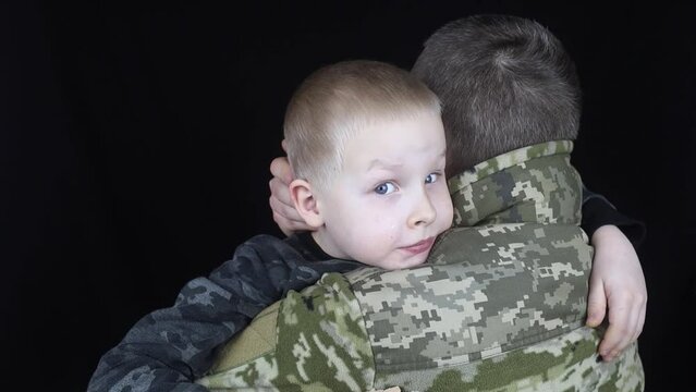War in Ukraine. Military and children. Ukrainian soldier hugs a child. Army protects country population from invaders. Terrorist activities in the country. Camouflage uniform of Ukrainian military