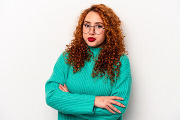 Young ginger caucasian woman isolated on white background blows cheeks, has tired expression....